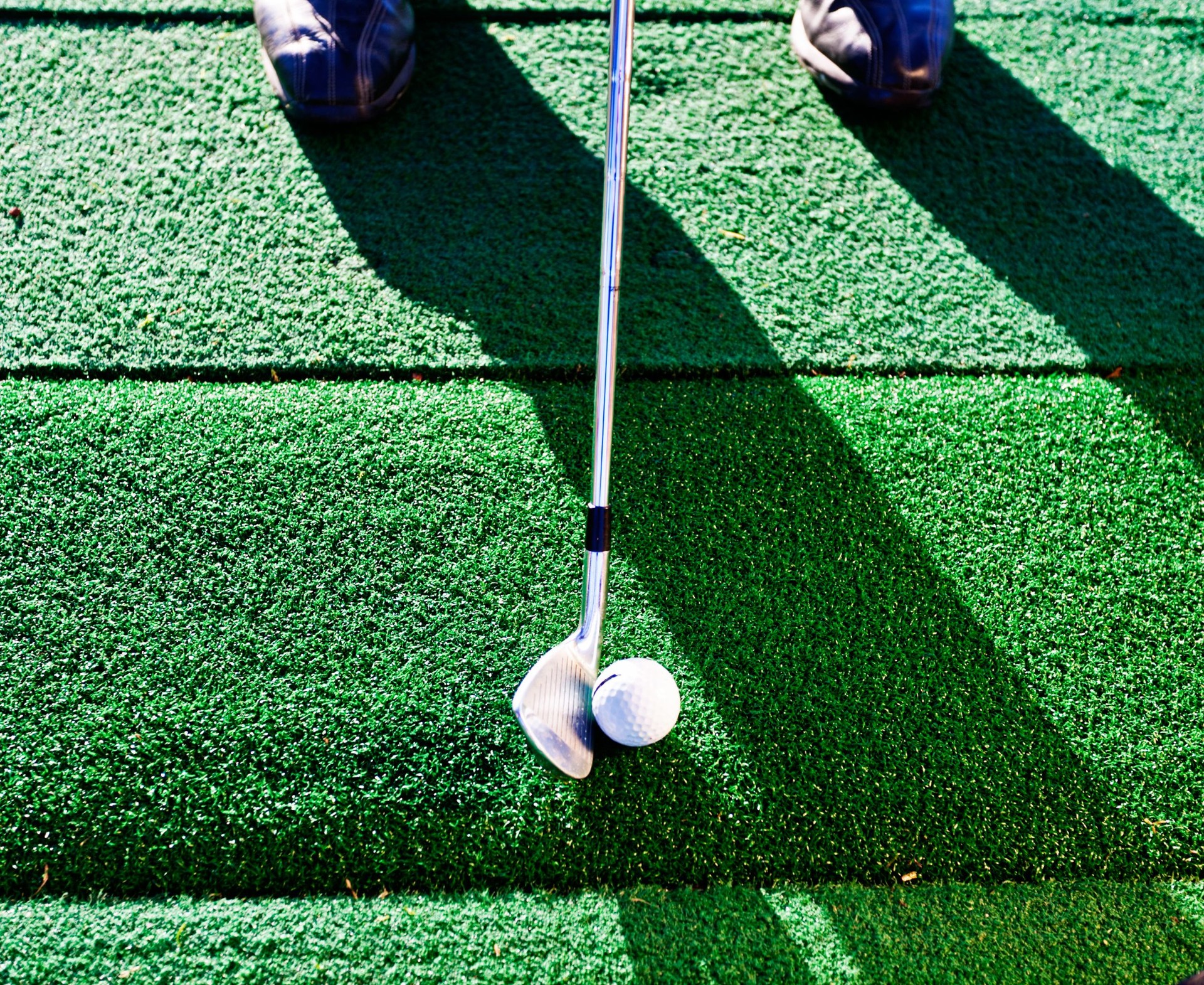 Golf club about to hit ball at driving range